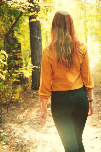 美丽的红头发女人在秋天的森林里散步. — 图库照片
