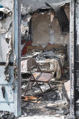 Bir yatak ve katlanır sandalye ile yanmış bir yatak odasına kapıdan görüntülemek