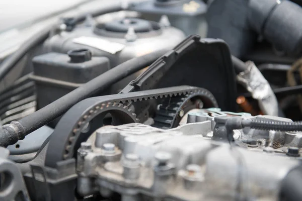 The timing belt of an automobile engine is visible on the side of the engine.