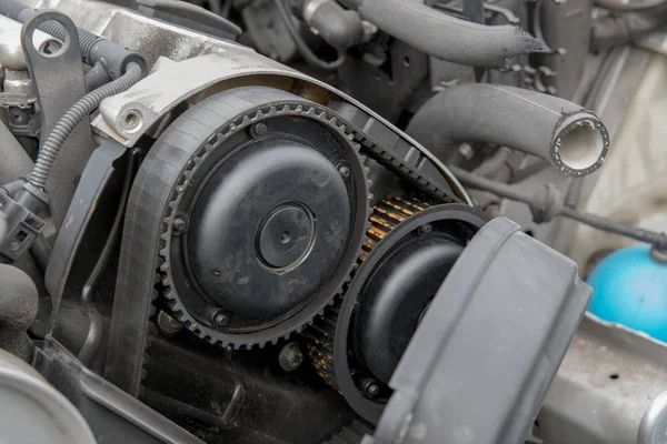 Automobile engine with side cover removed, exposing an old, cracked timing belt