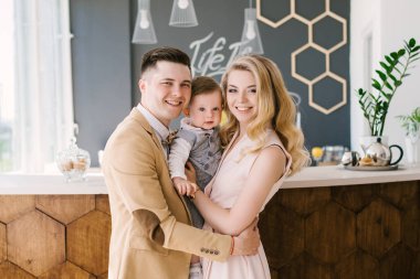 Güzel anne bir yaşındaki çocuklarının evde pastel renklerde güzel bir iç ile gülümse. Aile bak. Mutlu Doğum günü partisi