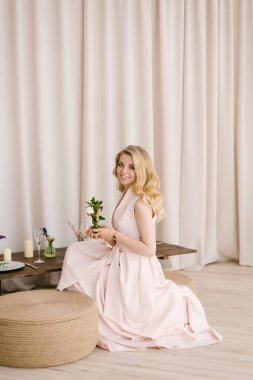 Hafif bir arka plan üzerinde hassas elbiseli kıvırcık sarı saçlı güzel bir genç kız portresi.