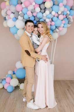 Pembe ve mavi balonlar arka plan üzerinde onların bir yaşındaki çocuk ile güzel anne gülümse. Aile bak. Mutlu Doğum günü partisi