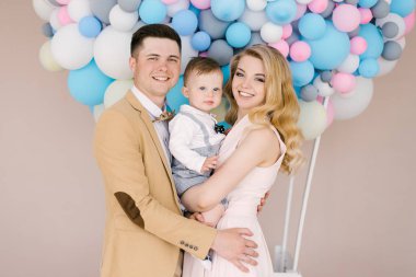 Pembe ve mavi balonlar arka plan üzerinde onların bir yaşındaki çocuk ile güzel anne gülümse. Aile bak. Mutlu Doğum günü partisi