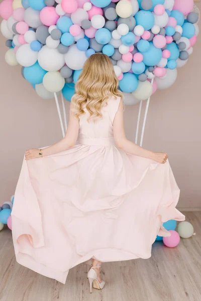 一个美丽的年轻女孩的肖像与卷曲的金发在充分成长 站在白色和蓝色气球的背景下 穿着浅色的衣服跳舞 — 图库照片