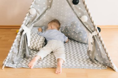 Bir çadırda şirin bir yaşında bebek KızıIderili. Alan, doğal ışık gölge derinliği. Çocuk odası iç gridir mavi ve beyaz