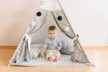 Bir çadırda oynarken şirin bir yaşında bebek KızıIderili. Alan, doğal ışık gölge derinliği. Çocuk odası iç gridir mavi ve beyaz