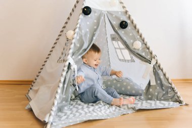 Bir çadırda oynarken şirin bir yaşında bebek KızıIderili. Alan, doğal ışık gölge derinliği. Çocuk odası iç gridir mavi ve beyaz