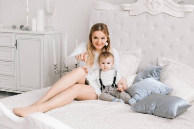 Anne ve birlikte evde bebeğim. Onlar üzerinde birlikte hafta sonu aydınlık oturma odası, tembel sabah, sıcak ve rahat sahne yatakta oturuyorlar. Seçici odak