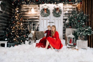 Noel ağacı yanında küçük oğlu ile genç beyaz anne. Kış tatilleri kutluyor ve bebekle oynarken kavramı.