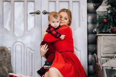 Noel ağacı yanında küçük oğlu ile genç beyaz anne. Kış tatilleri kutluyor ve bebekle oynarken kavramı.