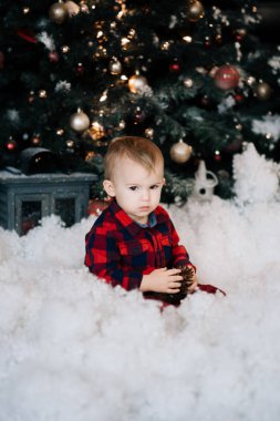 Karda oturup Noel dekor zemin üzerine güzel bir çocuk. Mutlu Noel ve yeni yıl kavramı