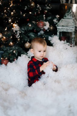 Karda oturup Noel dekor zemin üzerine güzel bir çocuk. Mutlu Noel ve yeni yıl kavramı