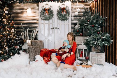 Noel ağacı yanında küçük oğlu ile genç beyaz anne. Kış tatilleri kutluyor ve bebekle oynarken kavramı.