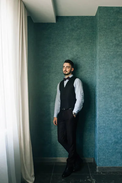 Morning of the groom. Groom morning preparation. Young and handsome groom getting dressed in a wedding shirt