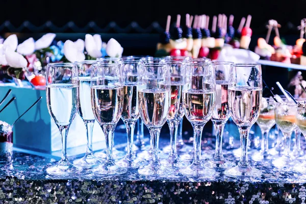 Celebration. Champagne glasses on the buffet table with snacks. Softly tinted, selective focus.