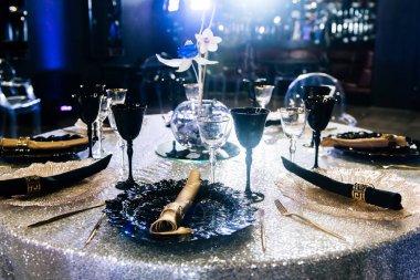 Bir etkinlik ya da düğün resepsiyonu için masalar hazır. Lokantada yemek hazırlayan lüks bir masa. Siyah ve altın bardaklar ve tabaklar.