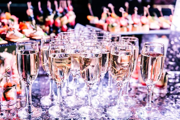 Celebration. Champagne glasses on the buffet table with snacks. Softly tinted, selective focus.