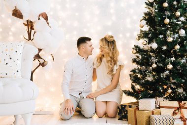 Noel ağacının fon karşı güzel bir genç aile portresi. Yeni yıl ve gülümsüyor çekici aile kutluyor