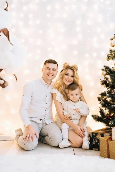在圣诞树的背景下 一个美丽的年轻家庭的肖像 迷人的父母和小儿子庆祝新年 — 图库照片