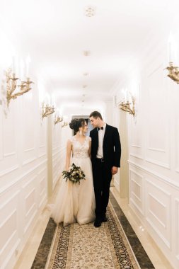 Mutlu genç ve sevgi dolu gelin ve damat bir lüks otel koridorda yürü. Düğün günü