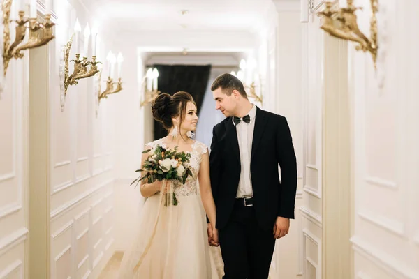 幸せな若い 愛情のある新郎新婦は 高級ホテルの廊下を歩きます 結婚式の日 — ストック写真
