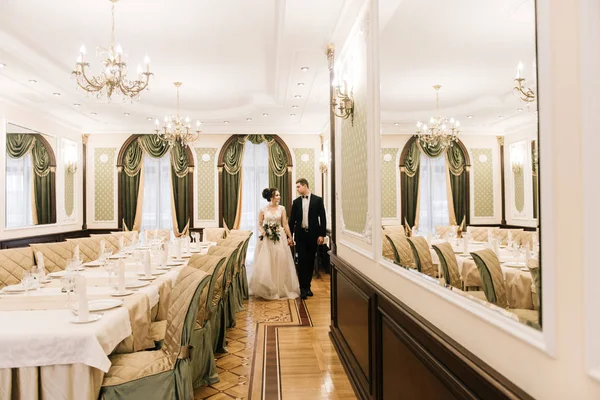 Happy young and loving bride and groom go to the Banquet hall of a luxury hotel. Wedding day
