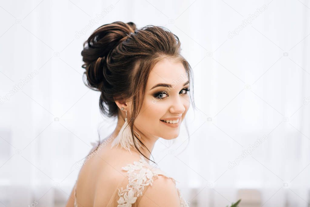 Pretty young girl.  Boudoir morning of the bride. Bride with luxurious hair and makeup. Accessories with feathers