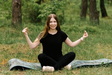 Egzersiz yapan esneyen kadın gülümseyerek yoga yapıyor.