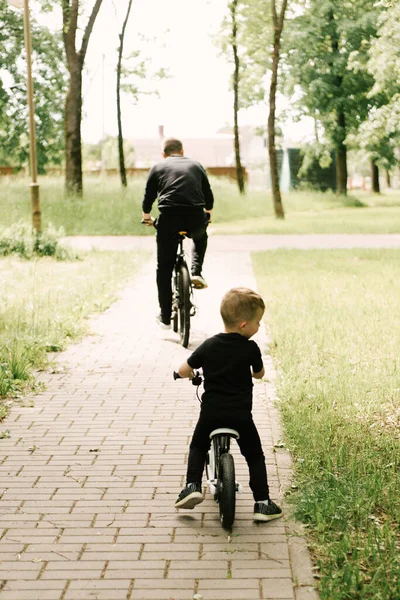 Feliz Niño Monta Una Bicicleta Con Padre Joven Parque —  Fotos de Stock