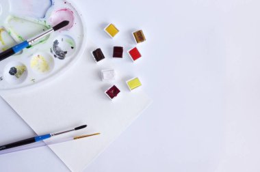 Beyaz arka plan üzerinde fırçalar ve suluboya kağıt ile suluboya boyalar için palet.