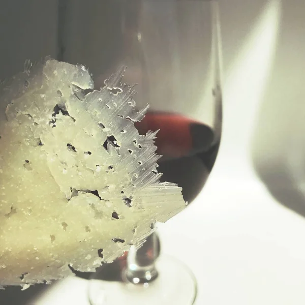 Un bicchiere di vino rosso e un sottile pezzo di formaggio — Foto Stock