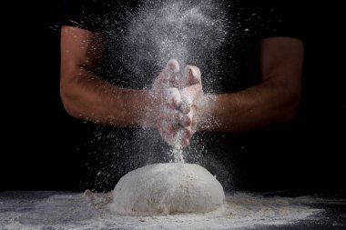 Alkışlar ve un hamur siyah arka plan üzerinde tutam erkek el yemek