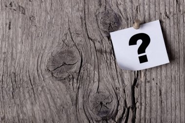 Soru işareti bir ahşap tahtası veya ağaç raptiye ile sabitlenmiş bir kağıt üzerinde