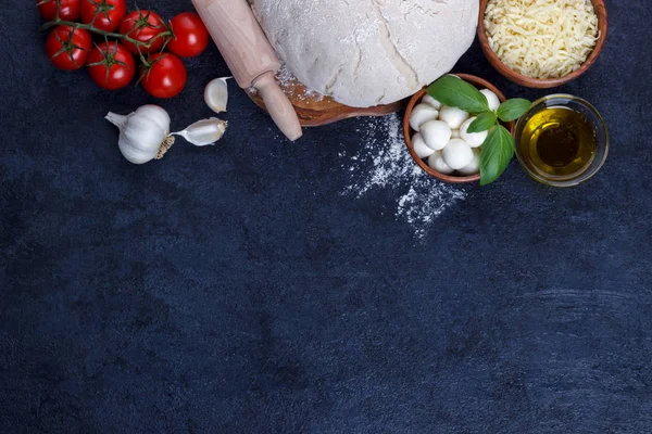 Pizza margherita ingridients çiğ hamur kiraz domates fesleğen zeytinyağı mozzarella peyniri karanlık taş mutfak masasında 