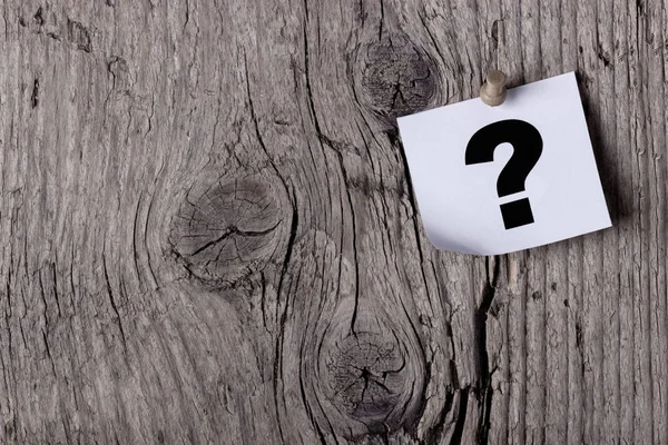 Soru işareti bir ahşap tahtası veya ağaç raptiye ile sabitlenmiş bir kağıt üzerinde