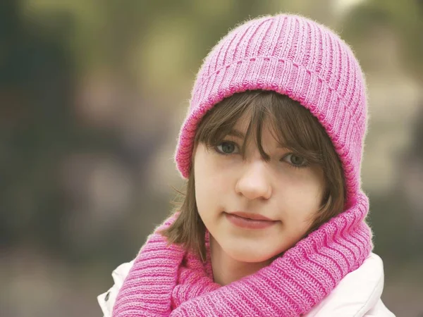 teenager girl with pink woolly hat looking at camera