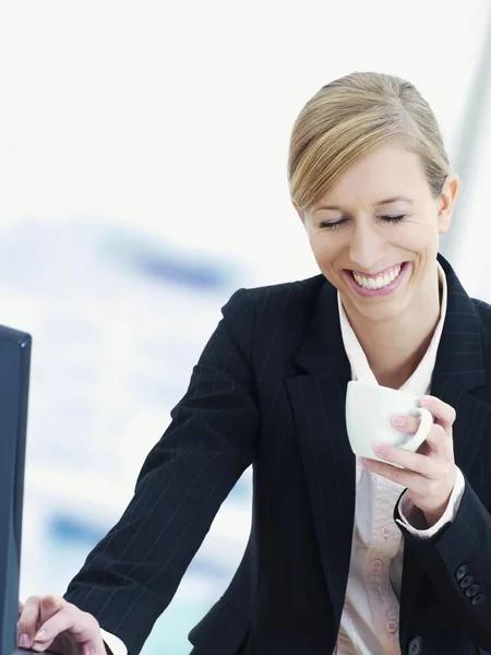 blonde business woman smiling and holding tea cup