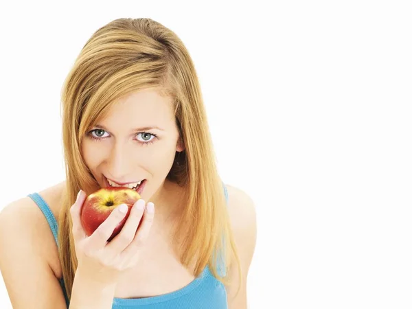 Ung Kvinna Äta Ett Äpple Och Tittar Kameran Stående Studio — Stockfoto