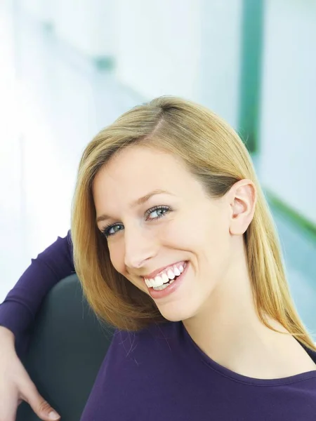 Młoda Kobieta Uśmiechając Się Patrząc Kamery Siedzi Krześle — Zdjęcie stockowe
