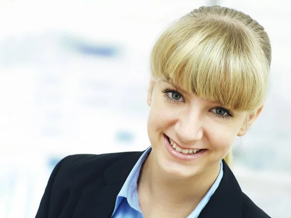 smiling blonde woman with hair bang looking at camera and wearing jacket