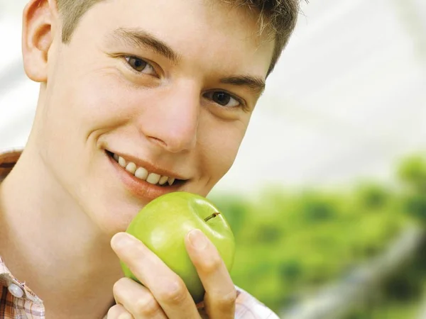 Tonåring Pojke Innehar Grönt Äpple Vid Munnen Och Ler Kamera — Stockfoto