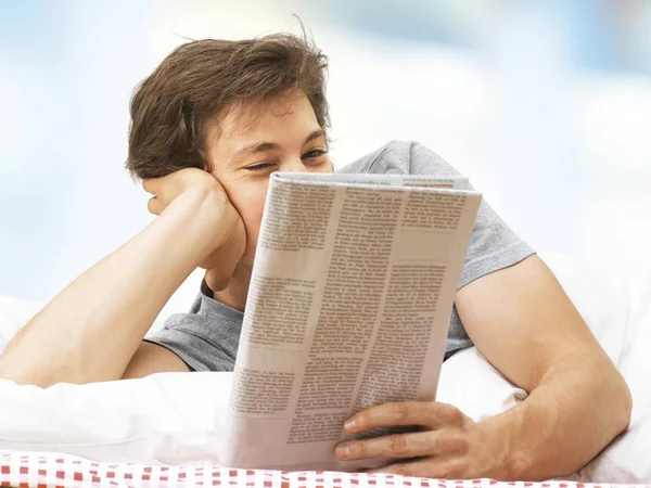 man reading newspaper and relaxing in bed