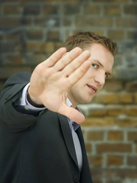 Businessman holding hand up in defensive manner, stop gesture