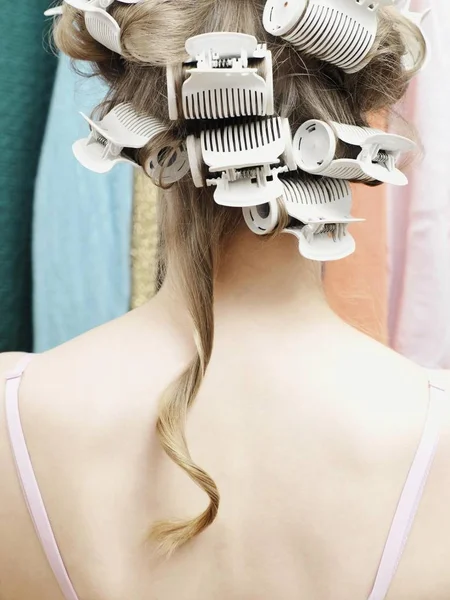 Woman wearing curlers with a single strand of hair hanging down