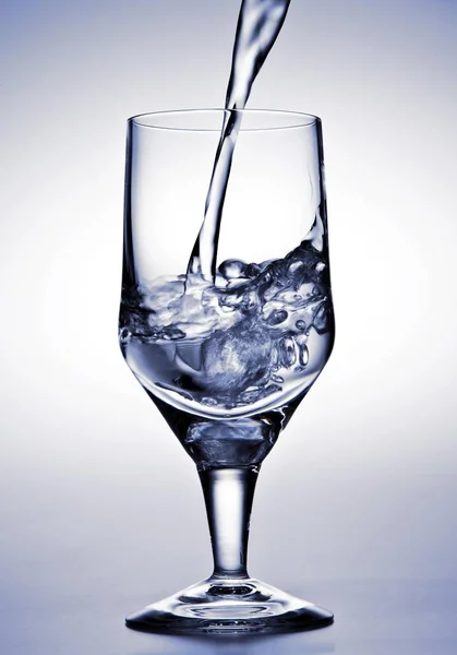 Water Wordt Gegoten Een Glas Tegen Witte Achtergrond — Stockfoto