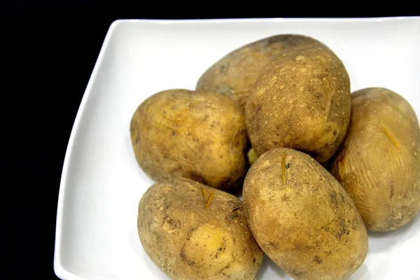 Batatas Cozidas Marrons Não Refinadas Uma Placa Branca Fundo Preto — Fotografia de Stock
