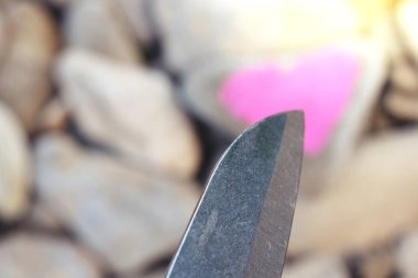 Bıçak dalış pembe kalp kesme taş parçası üzerinde ruj ile boyalı. Aşk ve iki kişi kıracak ve boşanma sonuna sembolü