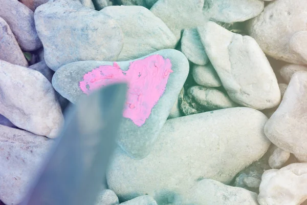Cutting knife diving pink heart painted with lipstick on piece of stone. Symbol of the end of love and of two people break up and divorce