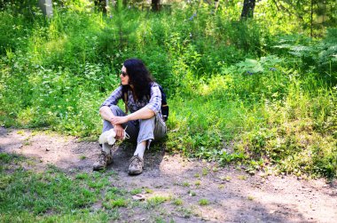 Kadın turist ile orman toprağa oturup sırt çantası